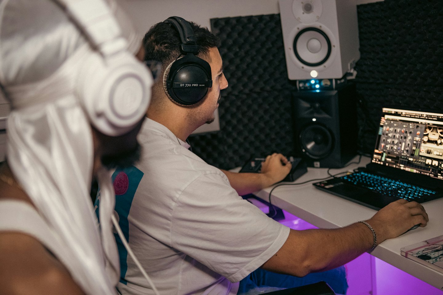 Man using audio mixing equipment and a laptop in studio.